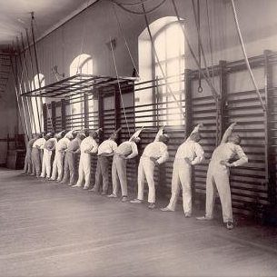 A group of men stretching on the Swedish bars at the Royal Central Institute of Gymnastics