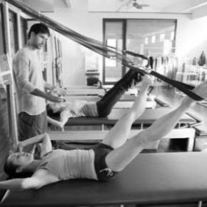 Two clients doing Pilates leg springs in class on the tower
