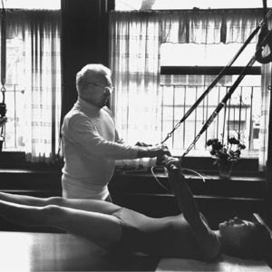 Joseph Pilates teaching a young woman the coordination exercise on the Cadillac.